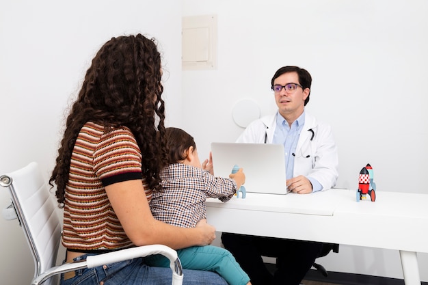 Foto gratuita médico de tiro medio hablando con el paciente.