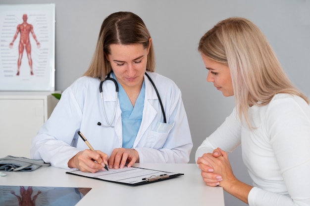 Foto gratuita médico de tiro medio hablando con el paciente