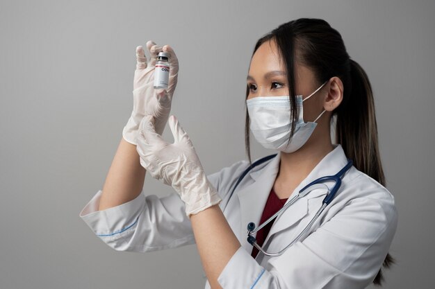 Médico de tiro medio con mascarilla sosteniendo vial