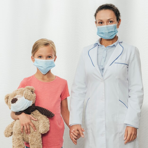 Médico de tiro medio y niño cogidos de la mano