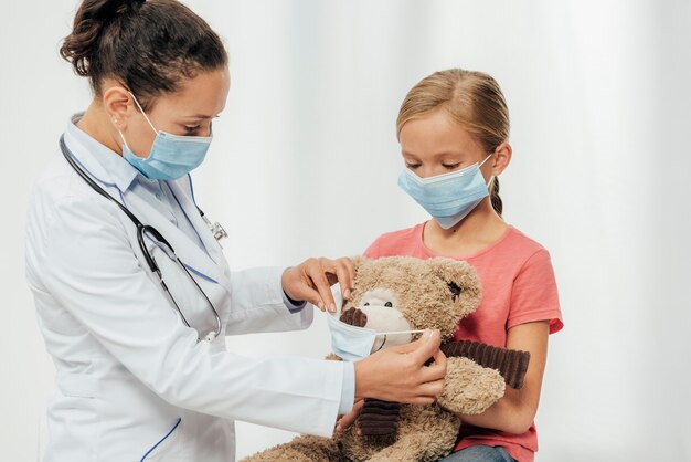 Médico de tiro medio y niño con máscaras