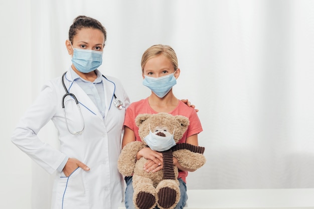 Médico de tiro medio y niño con oso