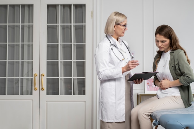 Médico de tiro medio y paciente charlando.