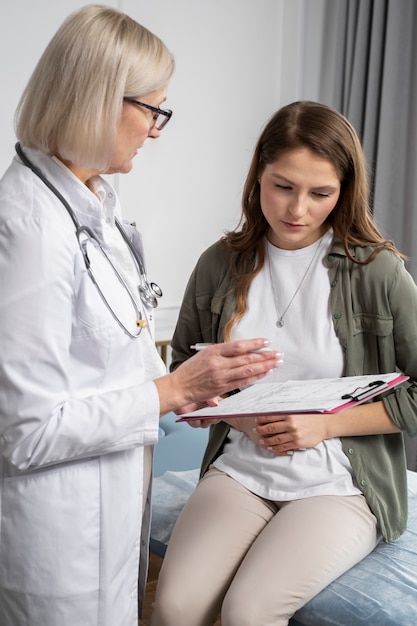 Médico de tiro medio y paciente conversando en la clínica