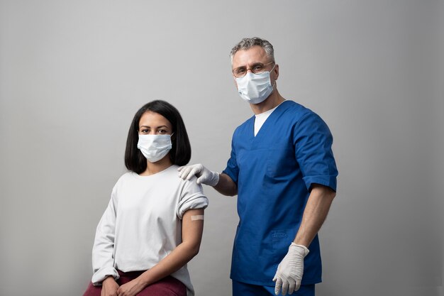 Médico de tiro medio y paciente con mascarillas.