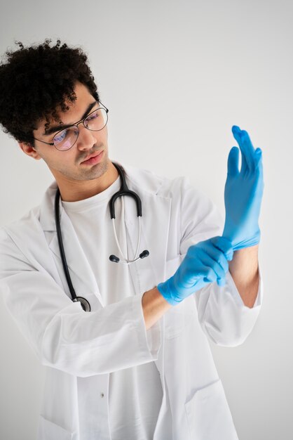 Médico de tiro medio poniéndose guantes
