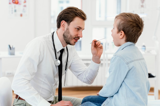 Médico de tiro medio revisando la boca del niño