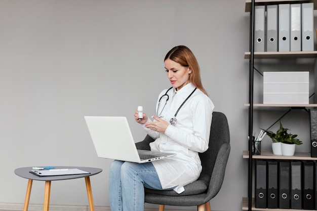 Médico de tiro medio sentado con computadora