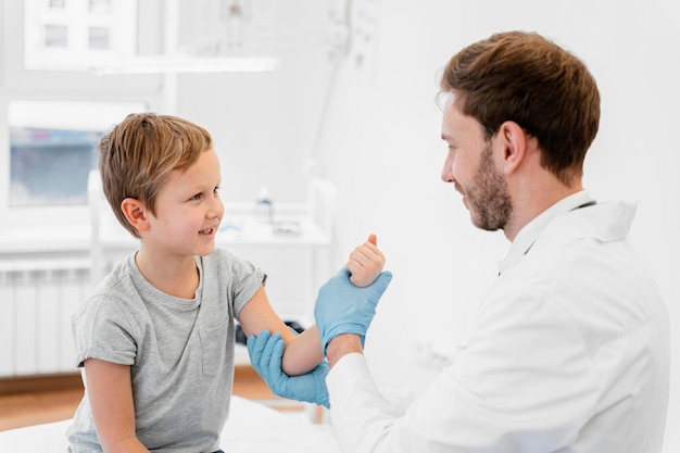 Médico de tiro medio sosteniendo el brazo del niño