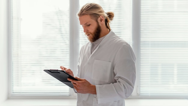 Médico de tiro medio tomando notas