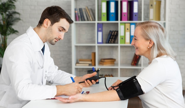 Médico de tiro medio tomando la presión arterial