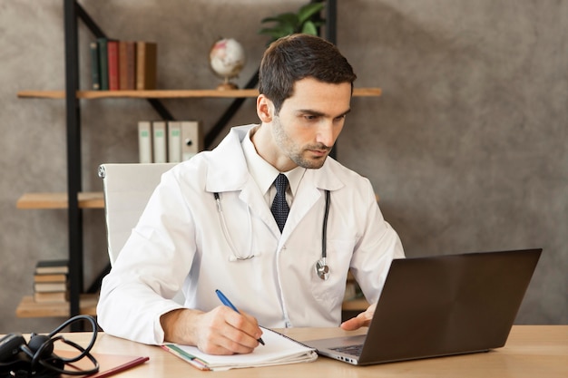 Médico de tiro medio trabajando en equipo portátil