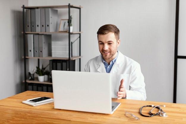 Médico de tiro medio trabajando con ordenador portátil