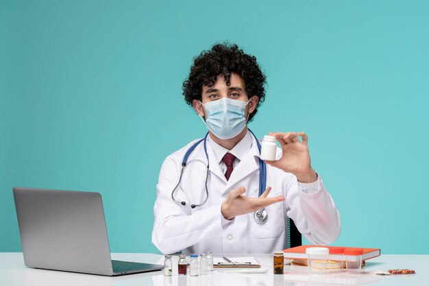 Médico trabajando de forma remota en la computadora lindo y guapo doctor en bata de laboratorio con máscara