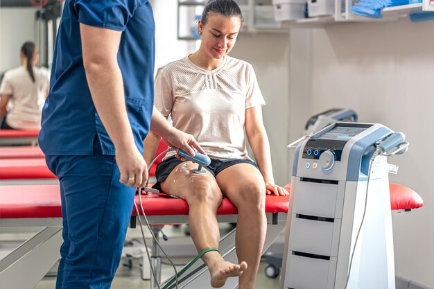 Médico usando una máquina para tratar las articulaciones de la rodilla de un paciente