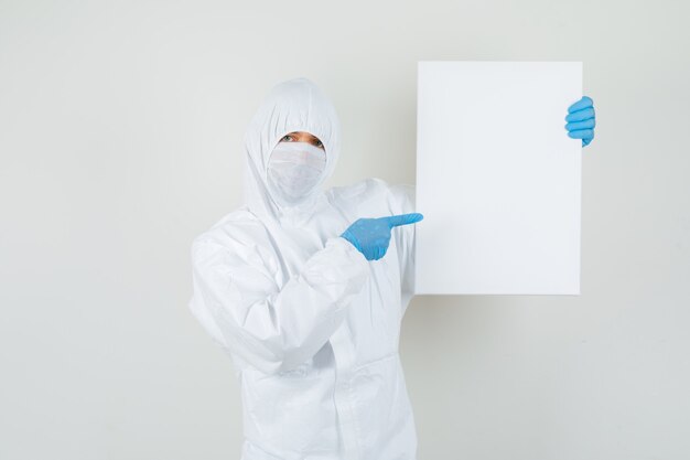 Médico varón apuntando al lienzo en blanco en traje protector