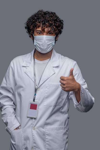 Foto gratuita médico varón en la cara que cubre mostrando un signo de aprobación