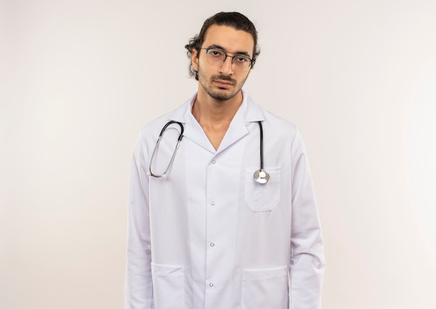 Médico varón joven cansado con gafas ópticas vistiendo túnica blanca con estetoscopio