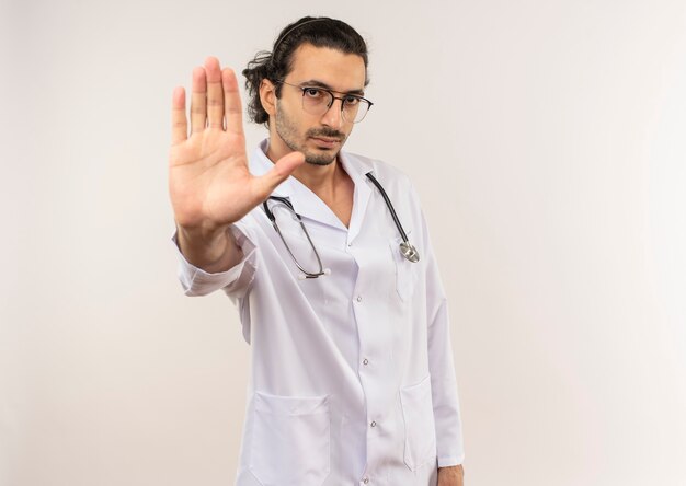 Médico varón joven con gafas ópticas vistiendo bata blanca con estetoscopio