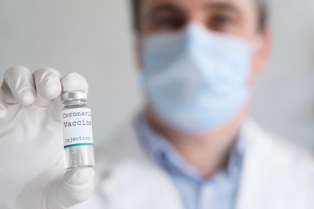 Médico varón sosteniendo el frasco de la vacuna