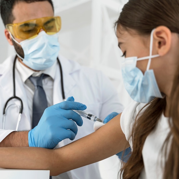 Médico varón vacunando a una niña de cerca
