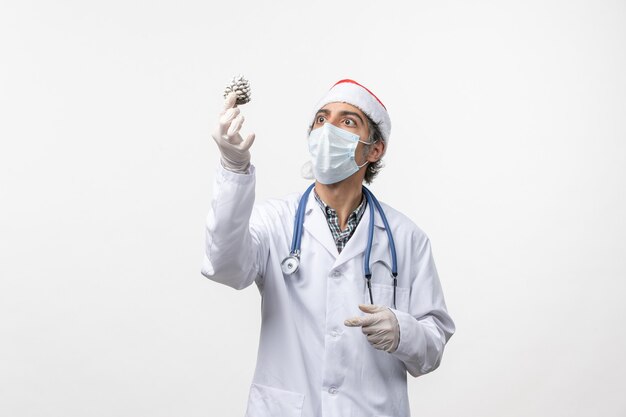 Médico varón de vista frontal con juguete de árbol de año nuevo en la pared blanca virus salud covid-