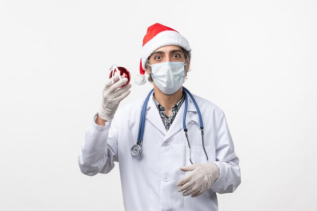 Médico varón de vista frontal con juguete de árbol de año nuevo en la pared blanca virus salud covid-