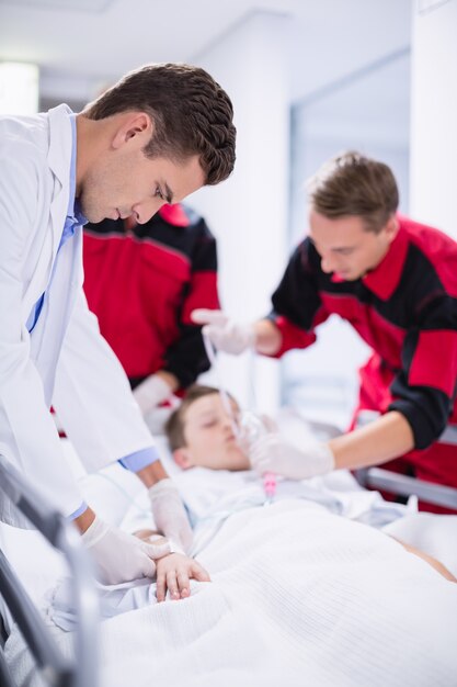 Los médicos ajustan la máscara de oxígeno mientras apresuran al paciente en la sala de emergencia