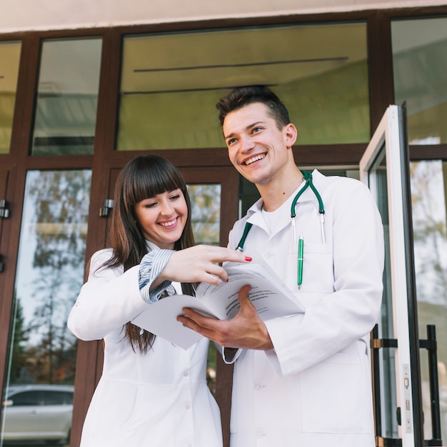 Foto gratuita médicos alegres de hombre y mujer con papeles