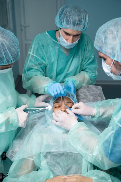 Médicos de alto ángulo que realizan rinoplastia.