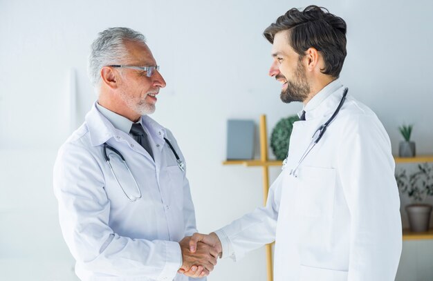 Médicos dándose la mano y mirándose
