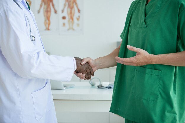 Médicos irreconocibles saludándose mutuamente estrechando manos