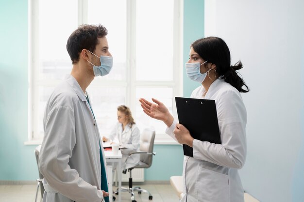 Médicos de tiro medio hablando con máscaras.