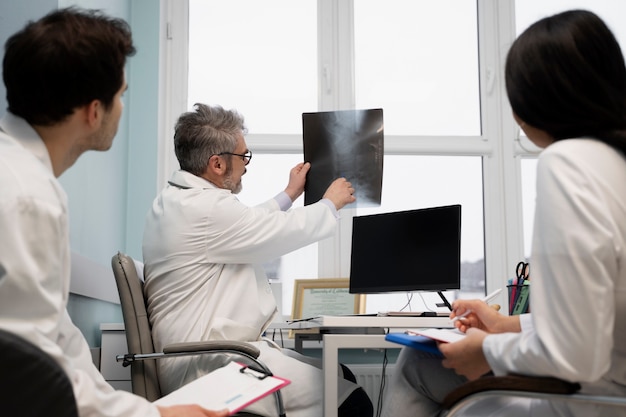 Médicos de tiro medio que miran una radiografía.