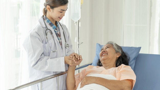 Foto gratuita los médicos se toman de la mano para alentar a las pacientes mayores de edad avanzada en el concepto médico y de atención médica femenina senior del hospital