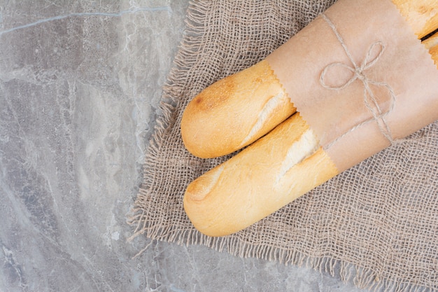 Foto gratuita medio corte de baguette francés sobre superficie de mármol