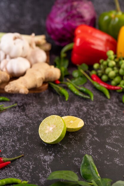 Medio limón en el suelo, con hojas de lima kaffir, chiles y jengibre.