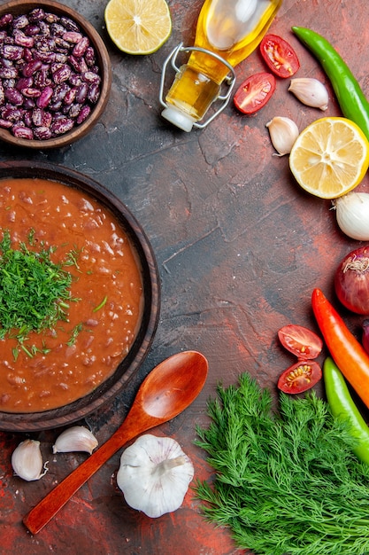 Medio tiro de botella de aceite de sopa de tomate frijoles limón y un montón de verde en la tabla de colores mezclados