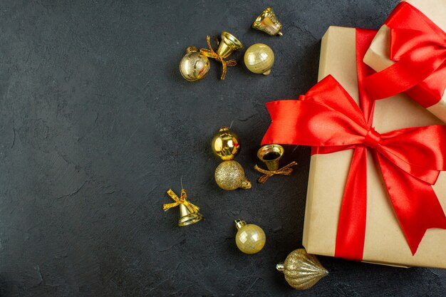 Medio tiro de caja de regalo con cinta roja y accesorios de decoración sobre fondo oscuro