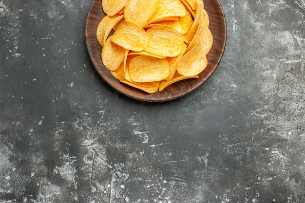 Medio tiro de deliciosas papas fritas caseras en una placa marrón sobre mesa gris