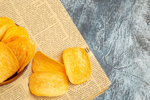 Medio tiro de deliciosas patatas fritas caseras en el periódico sobre la mesa gris