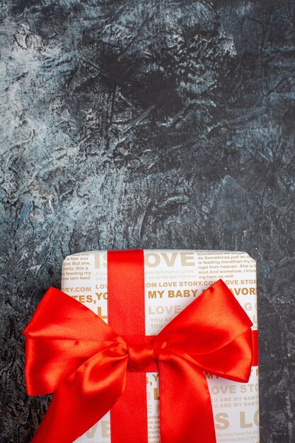 Medio tiro de hermosa caja de regalo atada con cinta roja sobre fondo oscuro helado
