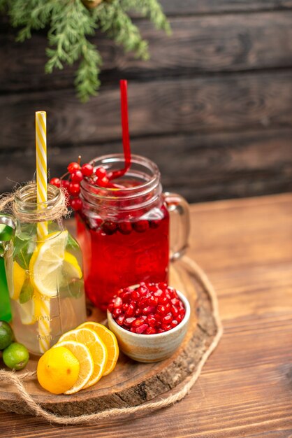 Medio tiro de jugos frescos orgánicos en botellas servidos con tubos y frutas sobre una tabla para cortar de madera