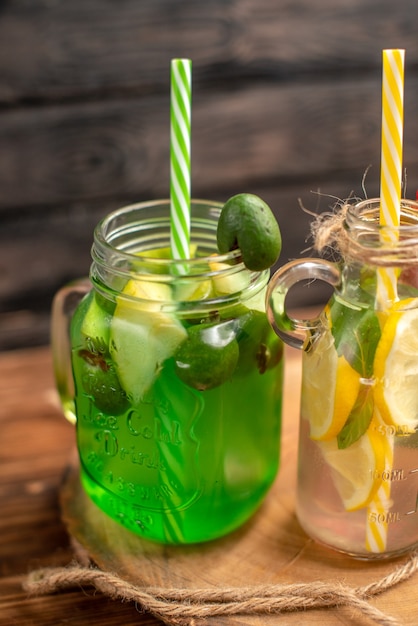 Medio tiro de jugos fuit orgánicos naturales en botellas servidas con tubos sobre una tabla de cortar de madera sobre una mesa marrón