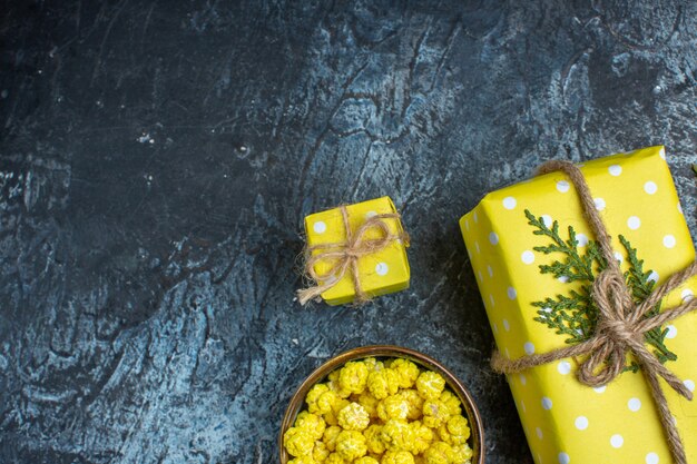 Medio tiro de limones frescos con hojas y galletas de caja de regalo amarilla en una olla marrón sobre fondo oscuro