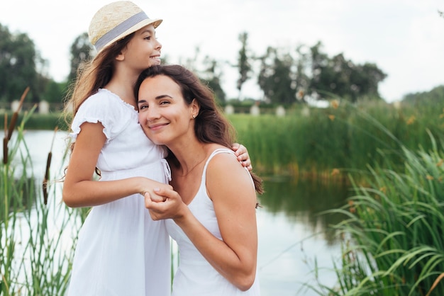 Medio tiro madre e hija abrazando por el lago