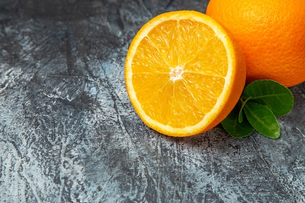 Medio tiro de naranjas frescas enteras y cortadas por la mitad sobre fondo gris