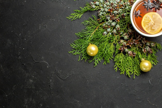 Medio tiro de una taza de té negro accesorios navideños y limones canela sobre fondo negro