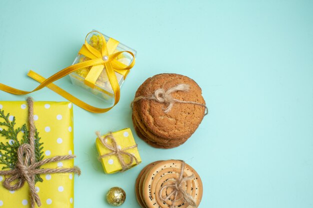 Medio tiro de varias deliciosas galletas apiladas y hermosas cajas de regalo amarillas sobre fondo verde pastel