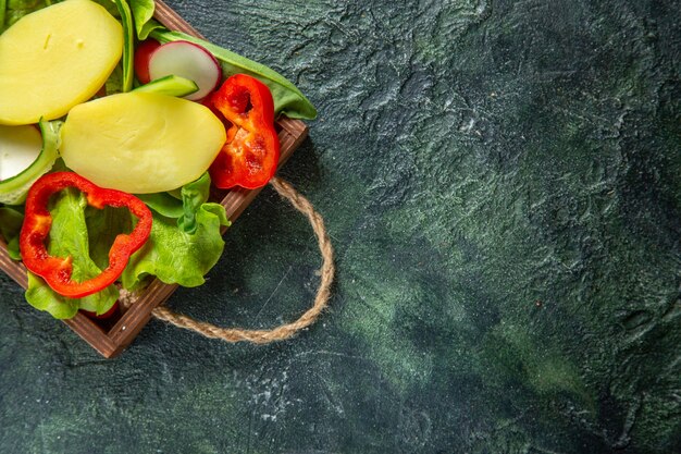 Medio tiro de verduras frescas picadas en una bandeja de madera en el lado derecho en la superficie de mezcla de colores con espacio libre